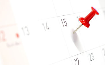 Ett kalenderblad där det sitter en röd nål på ett datum.