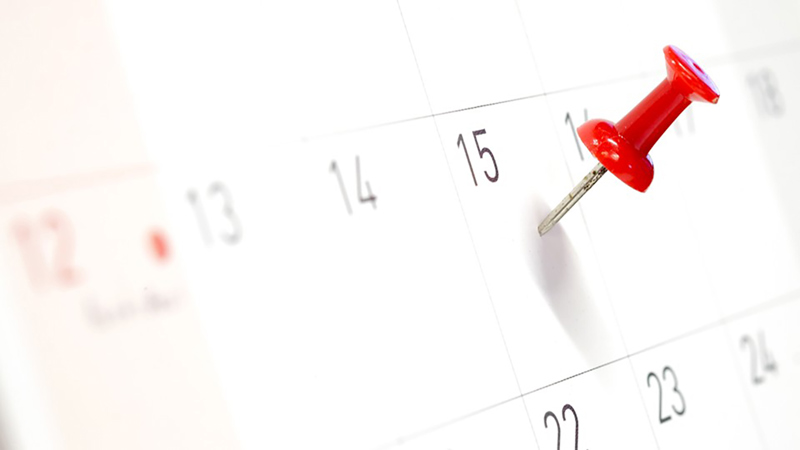 Ett kalenderblad där det sitter en röd nål på ett datum.
