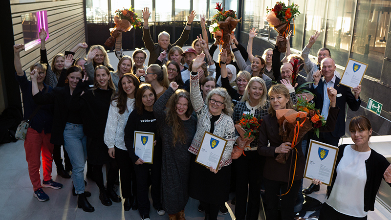 En grupp glada personer med diplom och blommor i händerna.