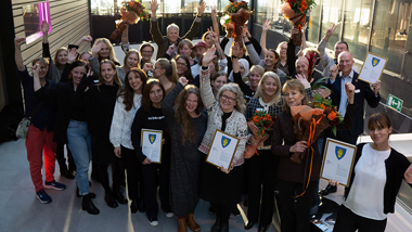 En grupp glada personer med diplom och blommor i händerna.