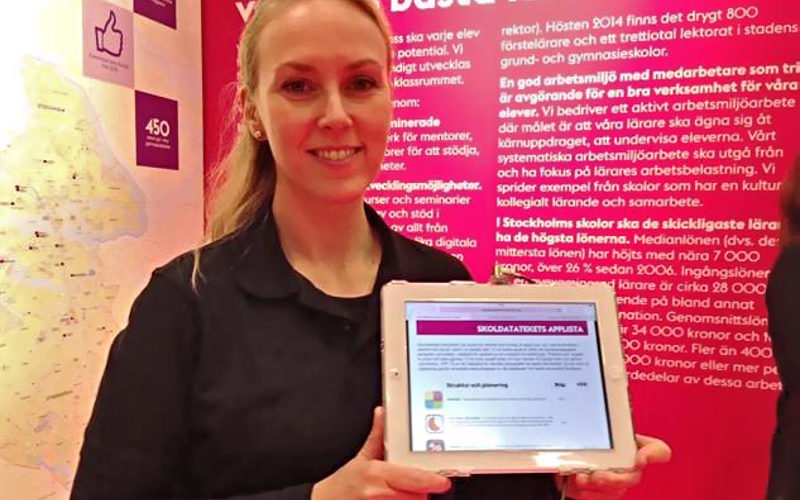 En kvinna visar upp en surfplatta där apptipsen syns.