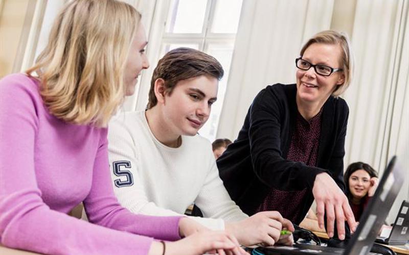 Två ungdomar och kvinnlig lärare tittar på datorskärm