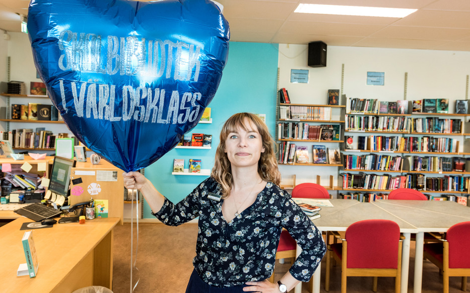 Kvinna i skolbibliotek håller i en ballong
