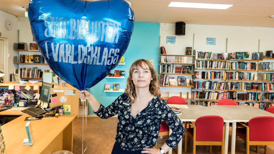 Kvinna i skolbibliotek håller i en ballong