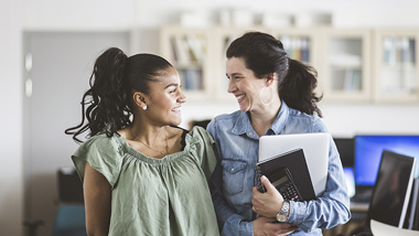 Två kvinnor tittar på varandra och skrattar.