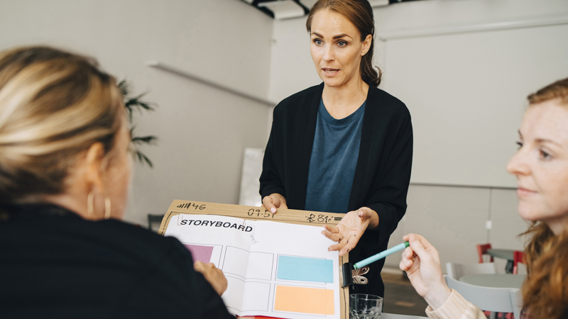 Tre kvinnor diskuterar runt en story board.