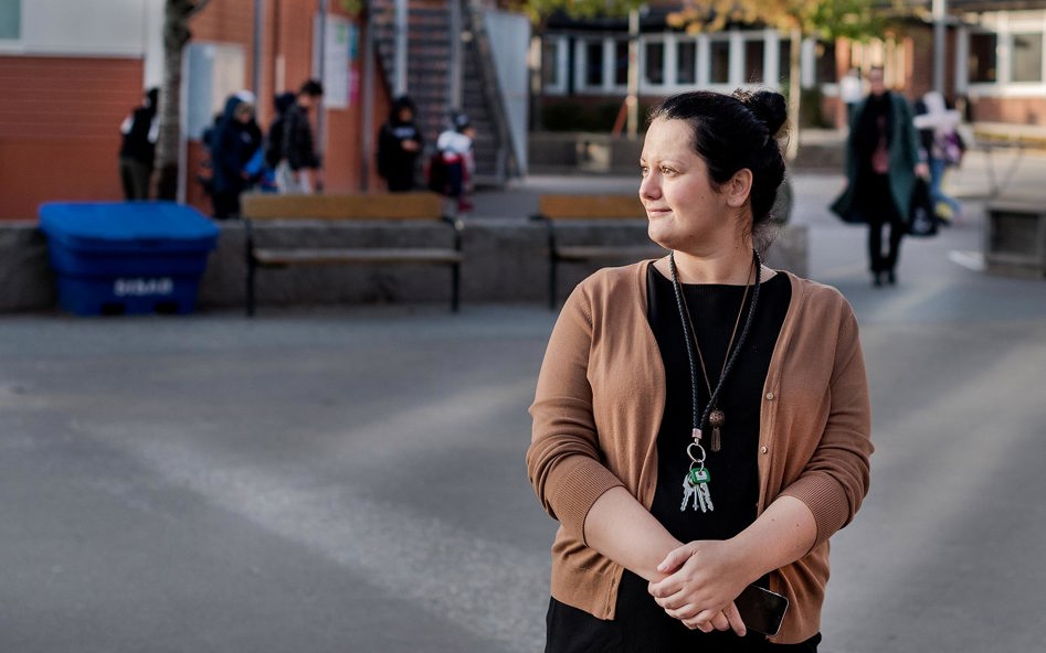 Kvinna i profil på skolgård. Har nyckelknippa om halsen.