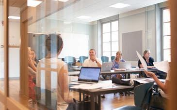 En grupp pedagoger runt ett bord med datorer framför sig