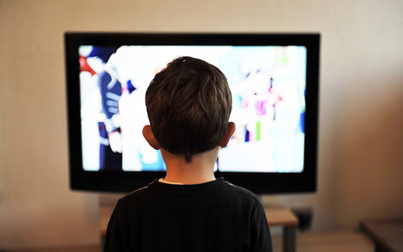En pojke bakifrån framför en tv-skärm