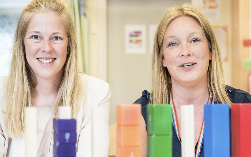 Två kvinnliga lärare i 40-årsåldern med klossar i olika färger framför sig i klassrummet.