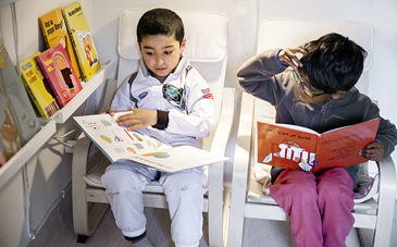 Två yngre pojkar sitter i varsin fåtölj och läser böcker