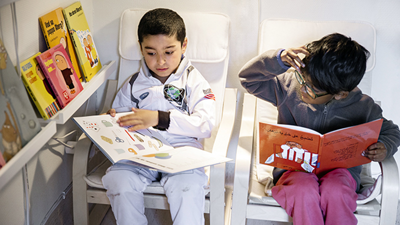 Två yngre pojkar sitter i varsin fåtölj och läser böcker