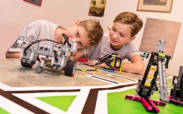 Två elever vid ett bord med en legorobot som de byggt.