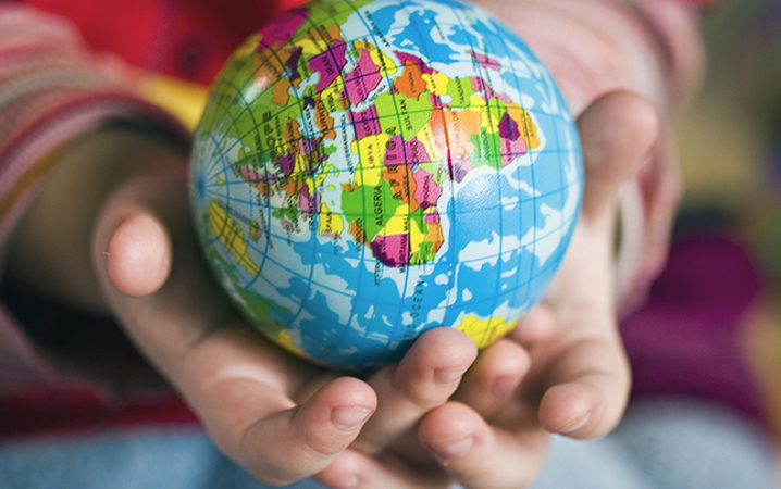 Två barnhänder håller i en liten jordglob.
