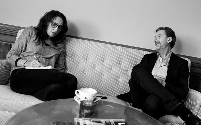 Jonas Aspelin sitter i en soffa bredvid skribenten Katarina Bjärvall som antecknar.