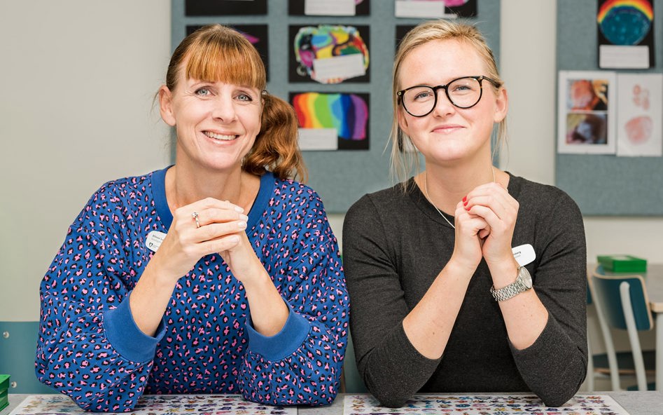 Två kvinnor bredvid varandra tittar in i kameran