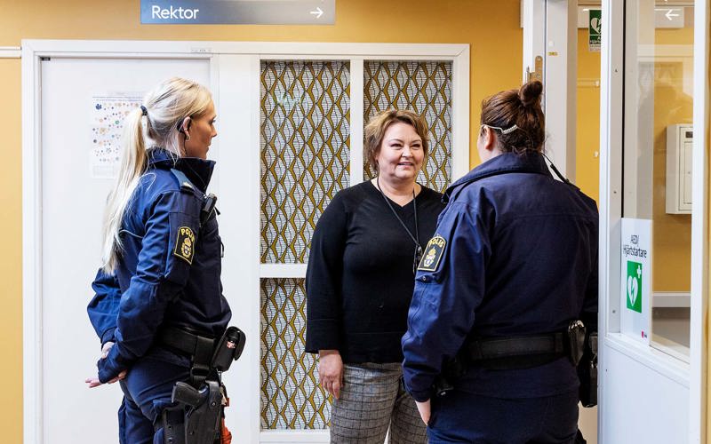 I en korridor står två poliser och en kvinna och diskuterar något.