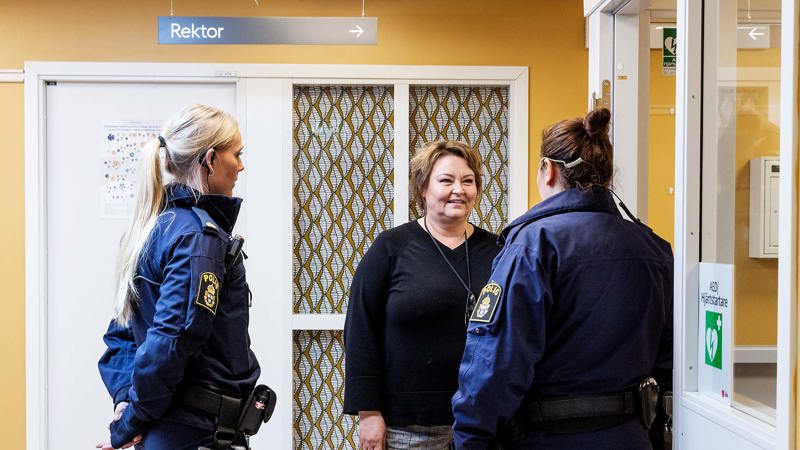 I en korridor står två poliser och en kvinna och diskuterar något.