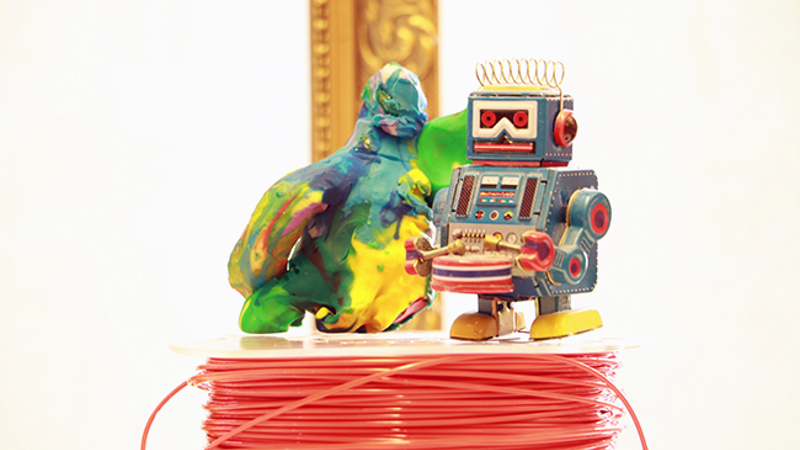 En robot och en figur i modellera står på en trådrulle.