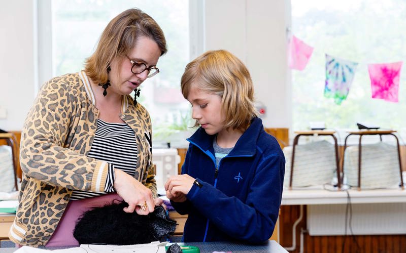 Lärare och elev arbetar gemensamt på ett tyg i pälsmaterial.