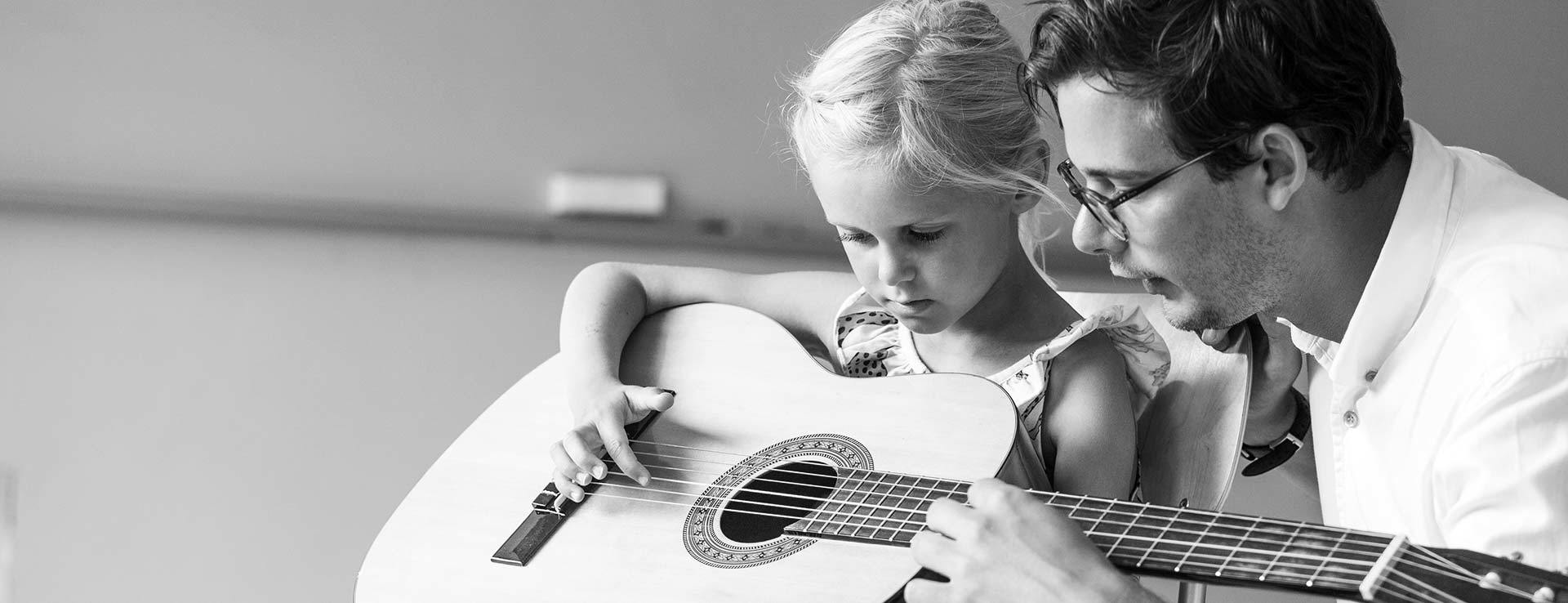 En musiklärare instruerar en elev i gitarr.