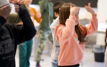 Barn står i klassrum och gör rörelse med händerna.
