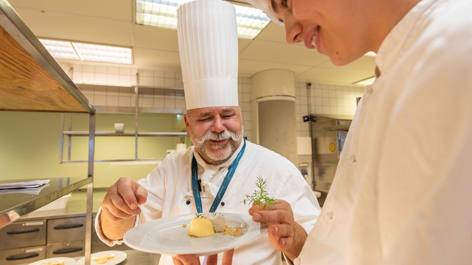 Kock och elev i restaurangkök. 