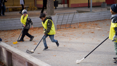 Tre barn spelar bandy utomhus.