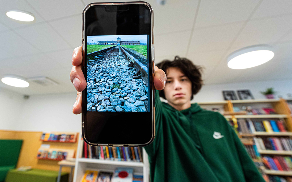 Alvarlig elev visar upp bild från Polenresan på sin mobiltelefon.