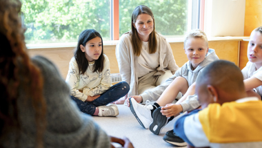 Lärare sitter på golvet tillsammans med elever.