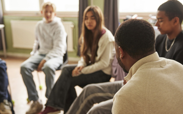 En grupp personer sitter i halvcirkel och pratar