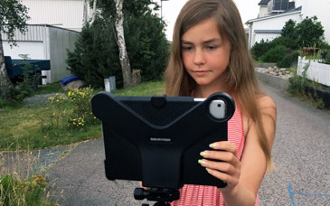 En flicka filmar med en Ipad som står på ett stativ.