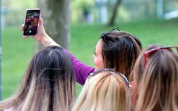 Fyra tjejer tar en selfie med mobiltelefonen utomhus.