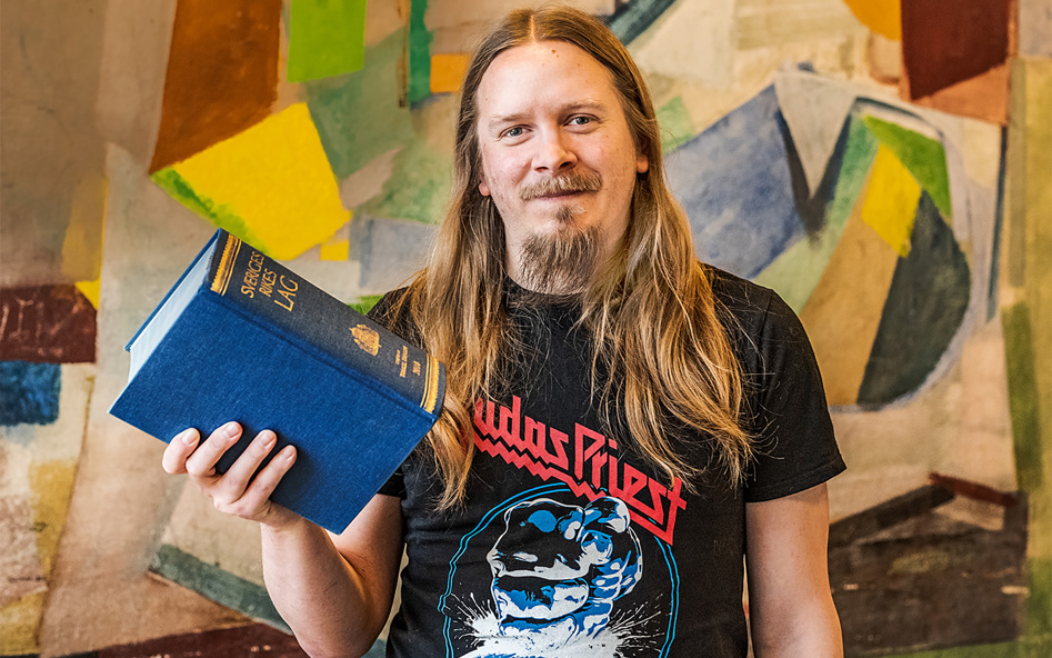 En person ler och håller upp boken Sveriges Rikes Lag.