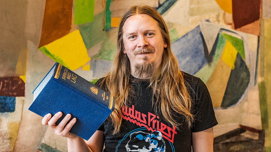 En person ler och håller upp boken Sveriges Rikes Lag.