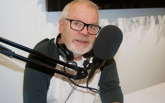 En man med hörlurar sitter vid en mikrofon.