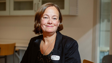 Leende kvinnlig lärare i solupplyst klassrum.