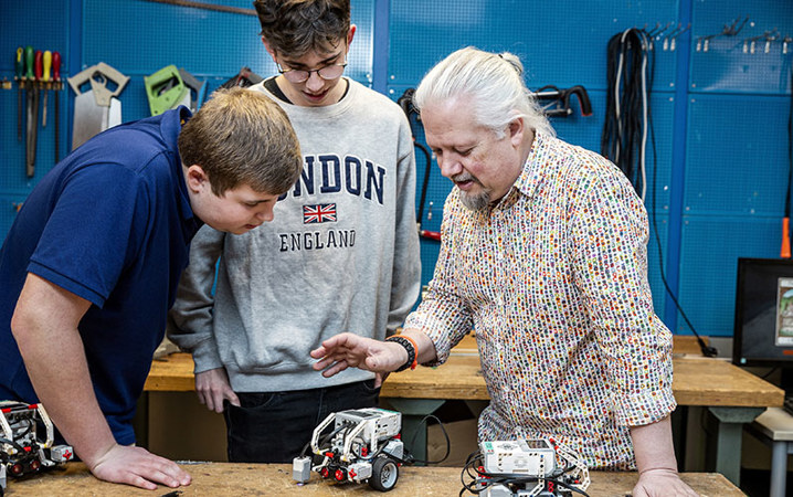 Engagerad lärare och två entusiastiska elever tittar på en robot tillverkad i lego.