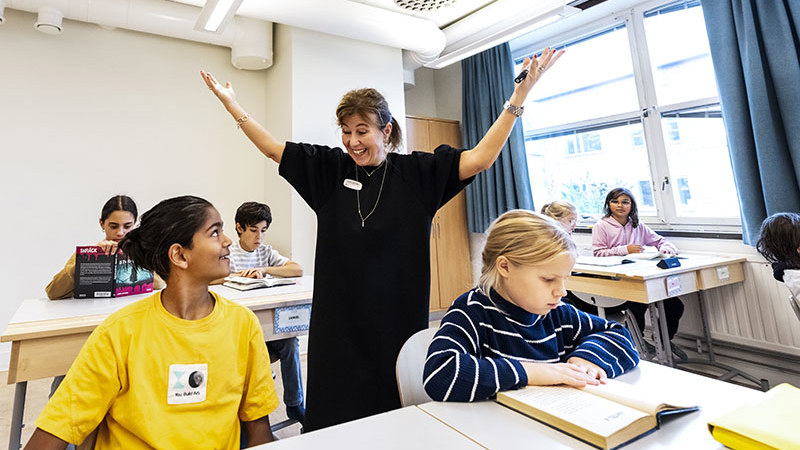 Entusiastisk lärare pratar med glad elev i färgglad tröja.