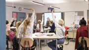 Elever i klassrum räcker upp handen.