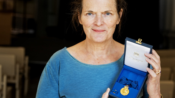 Närbild på en kvinna som håller en ask med en medalj i sin hand.