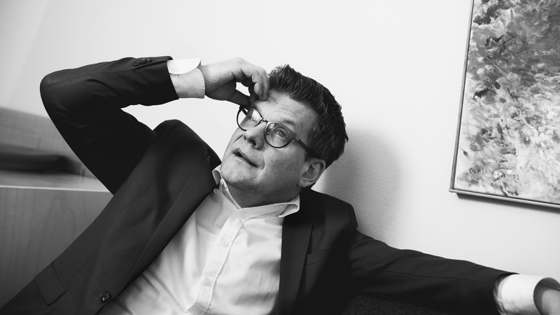 Svartvit bild på tänkande man i soffa, foto.