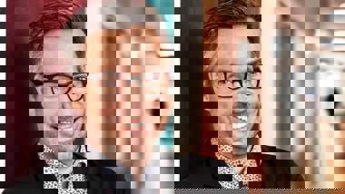 Rektor står i en skolkorridor och ler med armarna i kors.