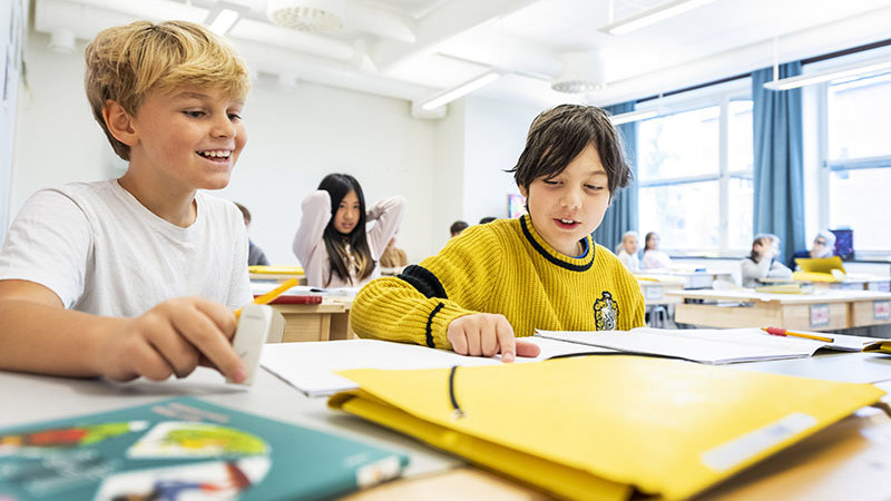 Två glada barn i klassrum.