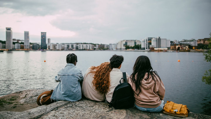 Fyra personer sitter på ett berg med utsikt över Stockholm.