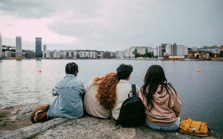Fyra personer sitter på ett berg med utsikt över Stockholm.