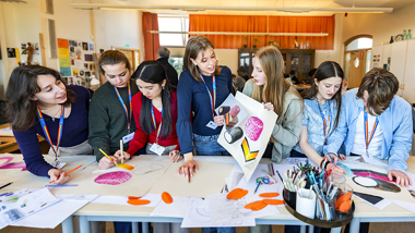 Elever visar upp målningar i glada färger. 