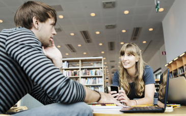 Två personer samtalar sittandes vid ett bord.