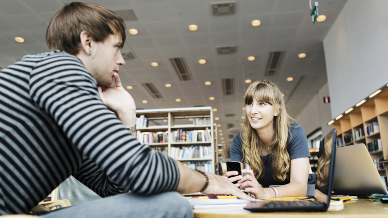 Två personer samtalar sittandes vid ett bord.