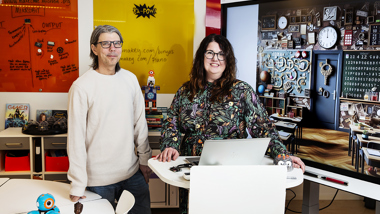 Två glada pedagoger i färgglatt klassrum.